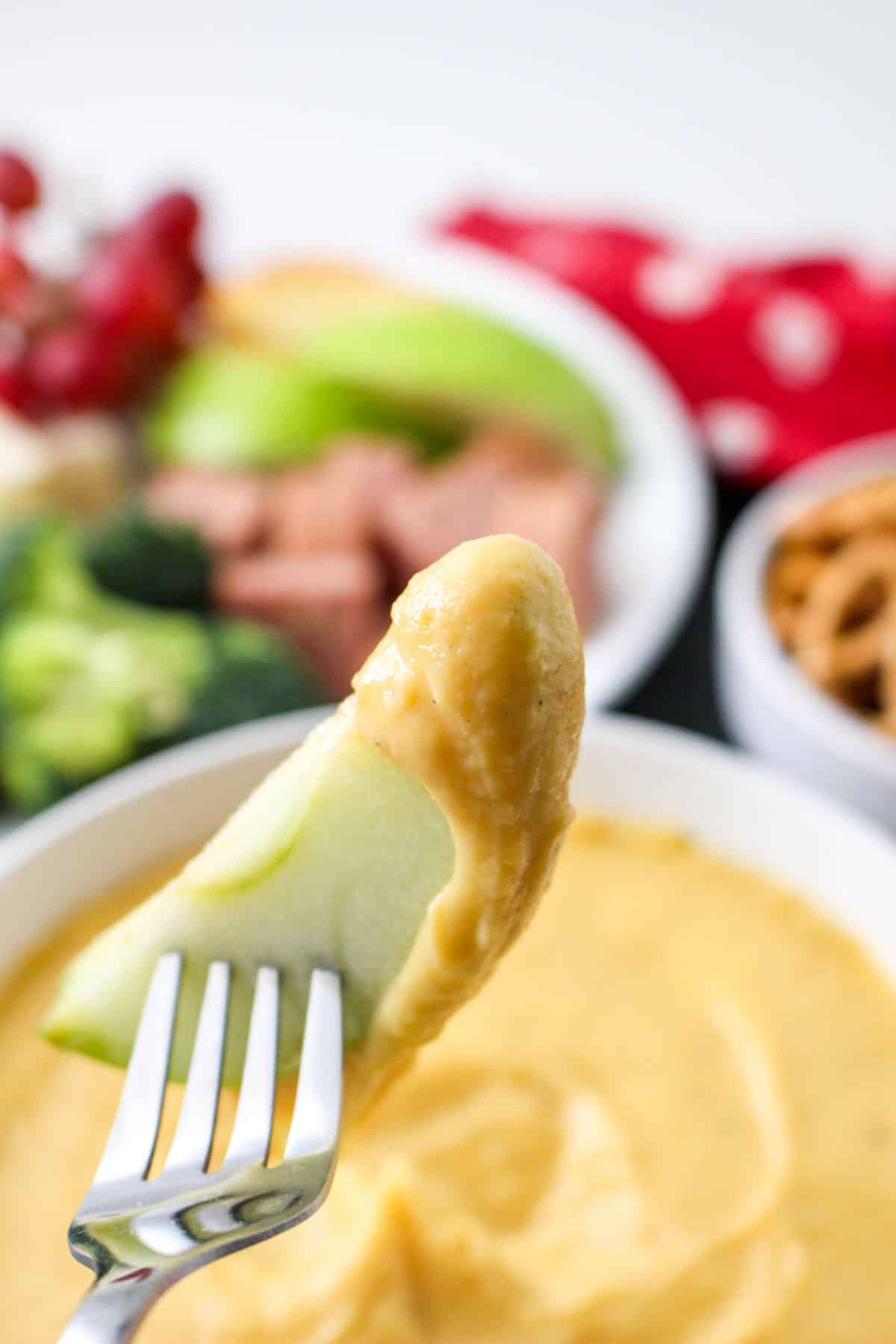 fork holding a fondue dipped apple slice.