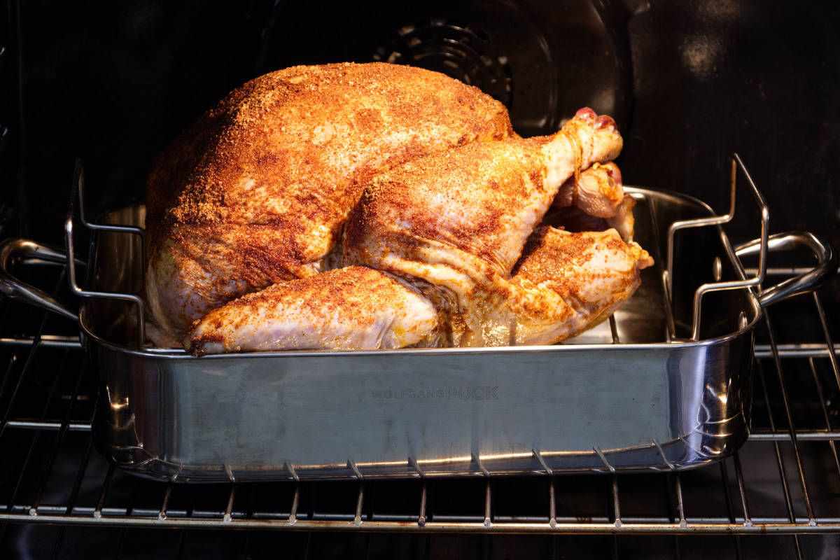 Whole turkey in a roasting pan in a convection oven.