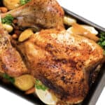 Whole turkey garnished with vegetables and apples, served with lemon slices and greens in baking dish.