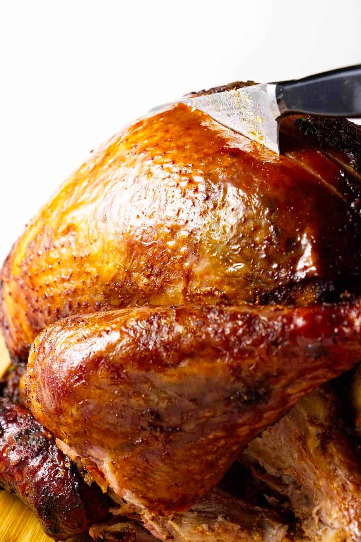 Knife carving a freshly roasted whole turkey.