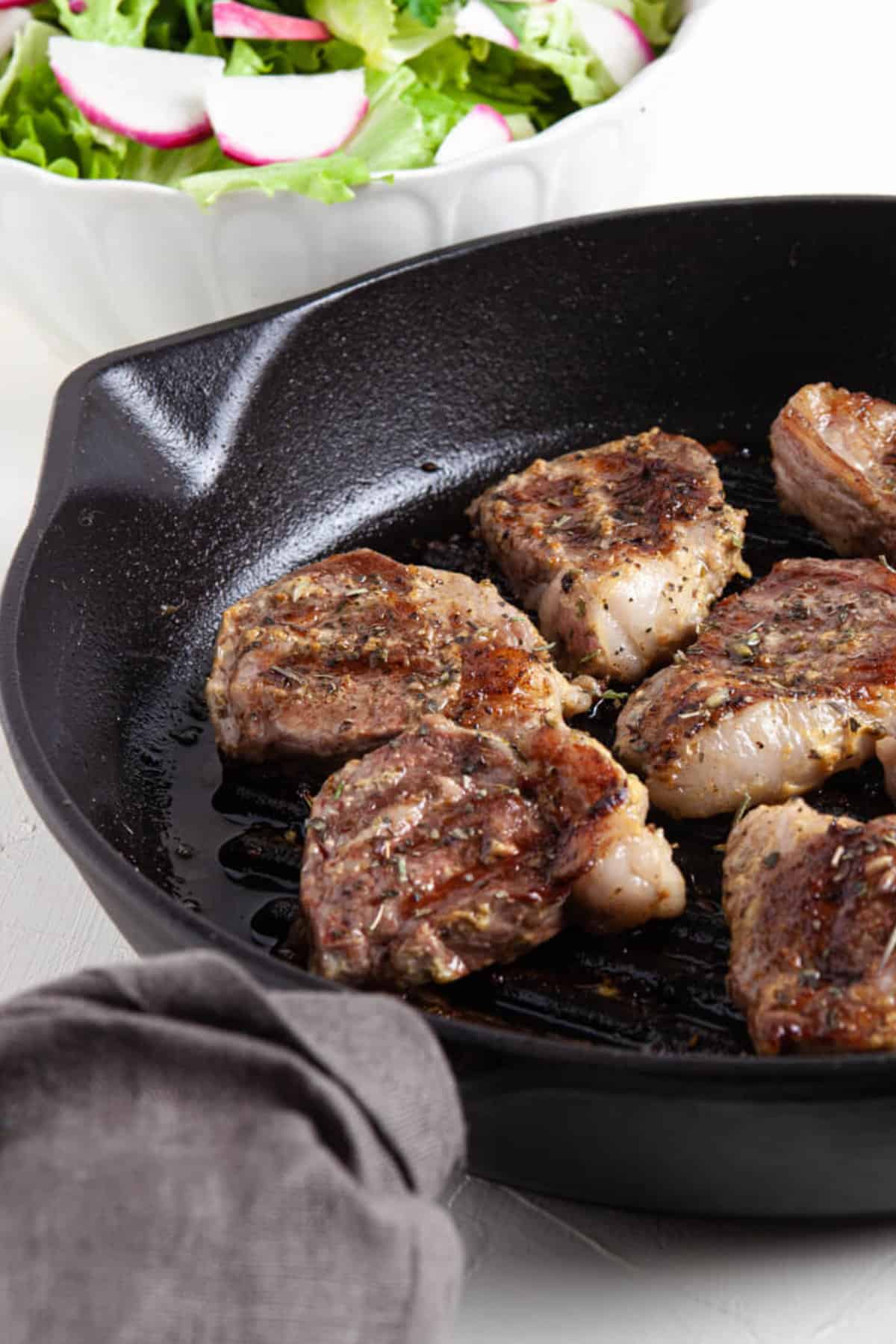 Pan seared lamb chops served in a cast iron skillet.