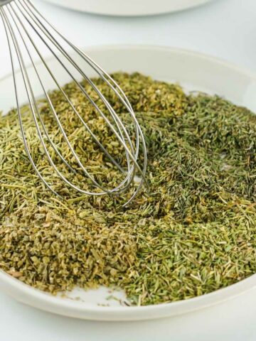 plate of herbes being blended with a whisk.