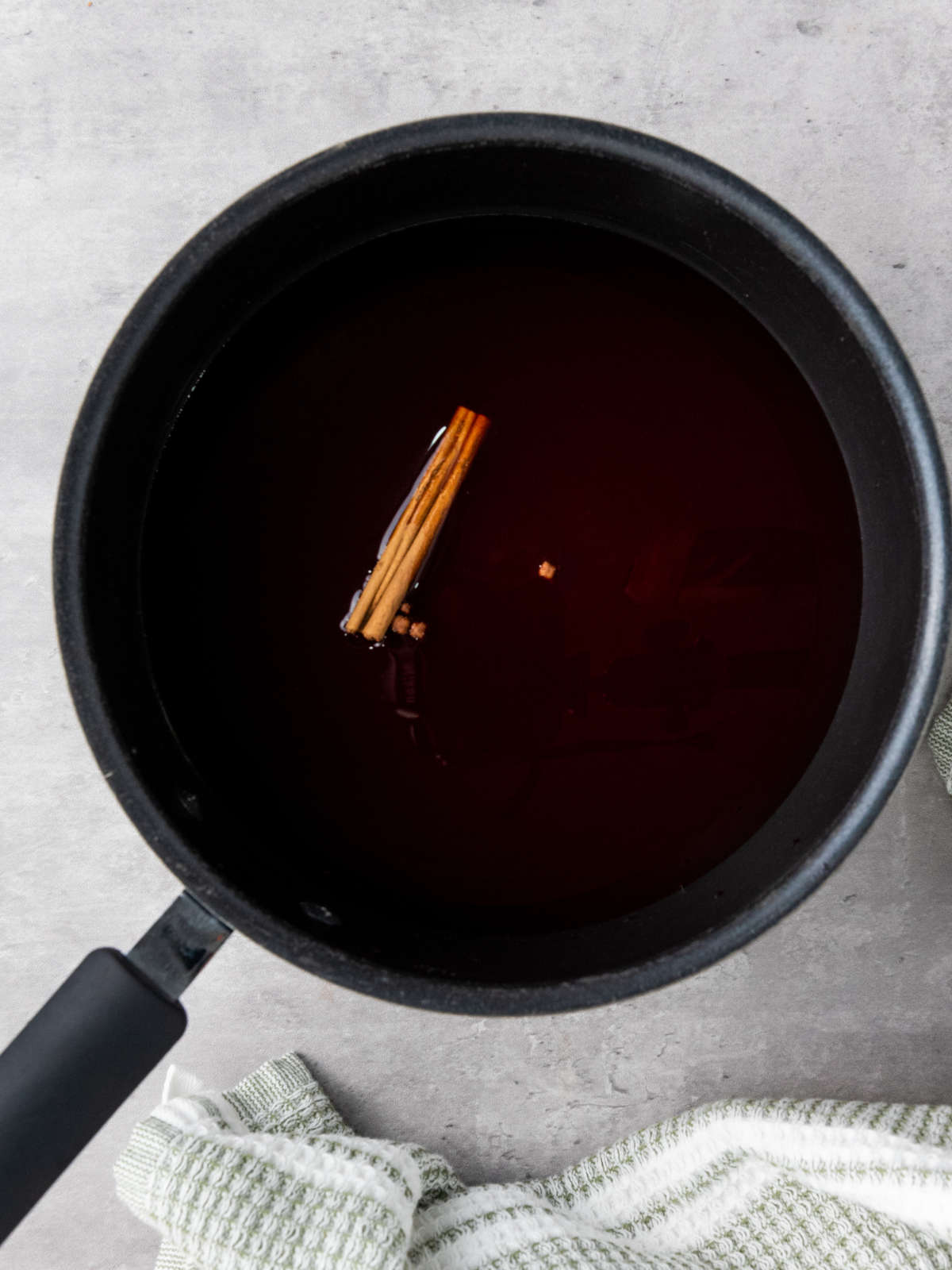 Wine and cinnamon sticks in a sauce pan.