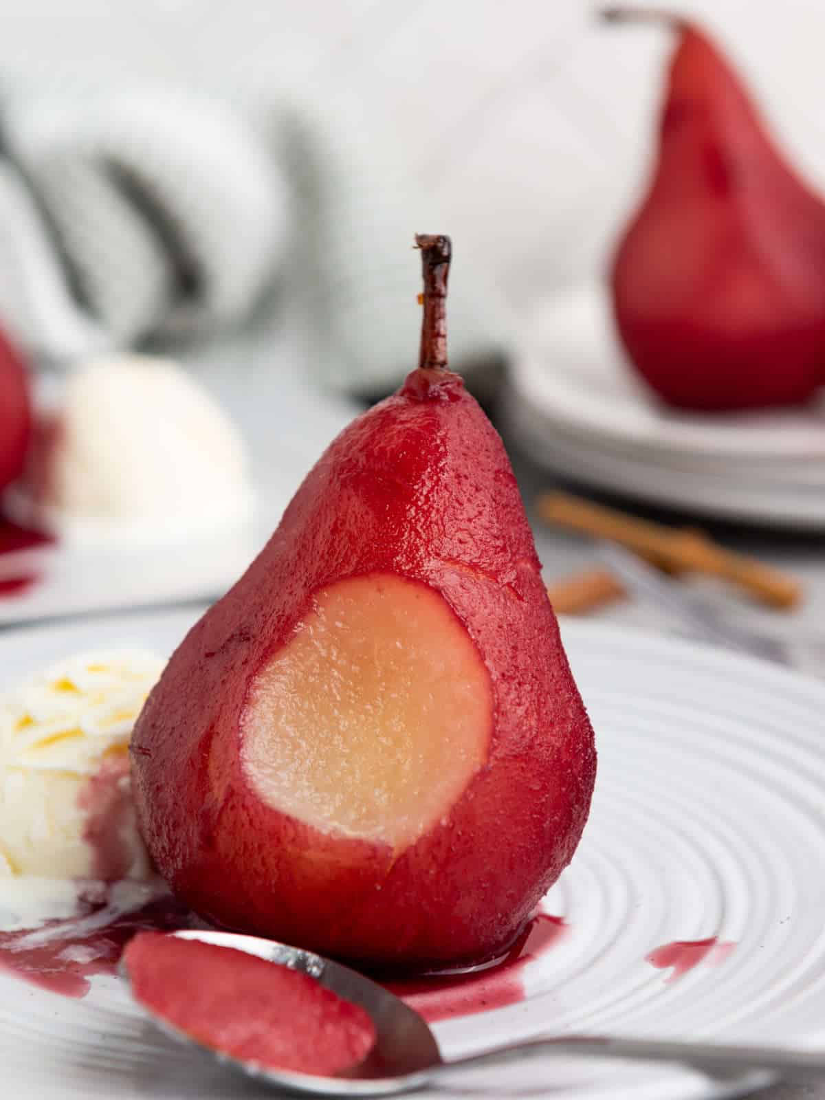 spoonful removed from a wine poached pear on a plate.