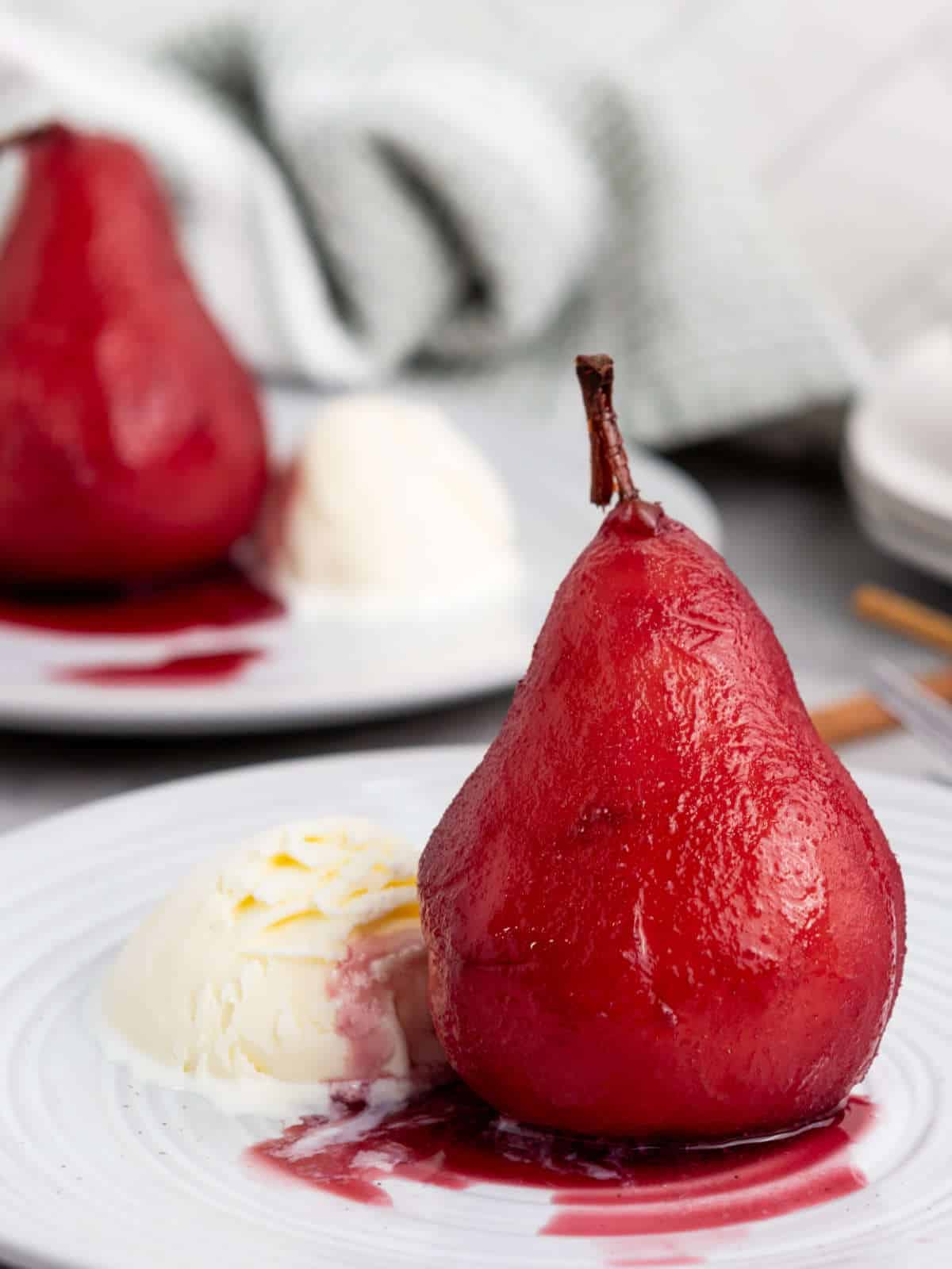 Marsala poached pear on a plate with vanilla ice cream.