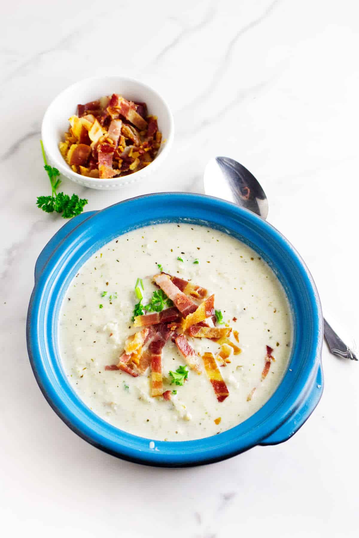 Mock potato soup (celery root soup) with bacon and parsley garnish in a soup bowl.