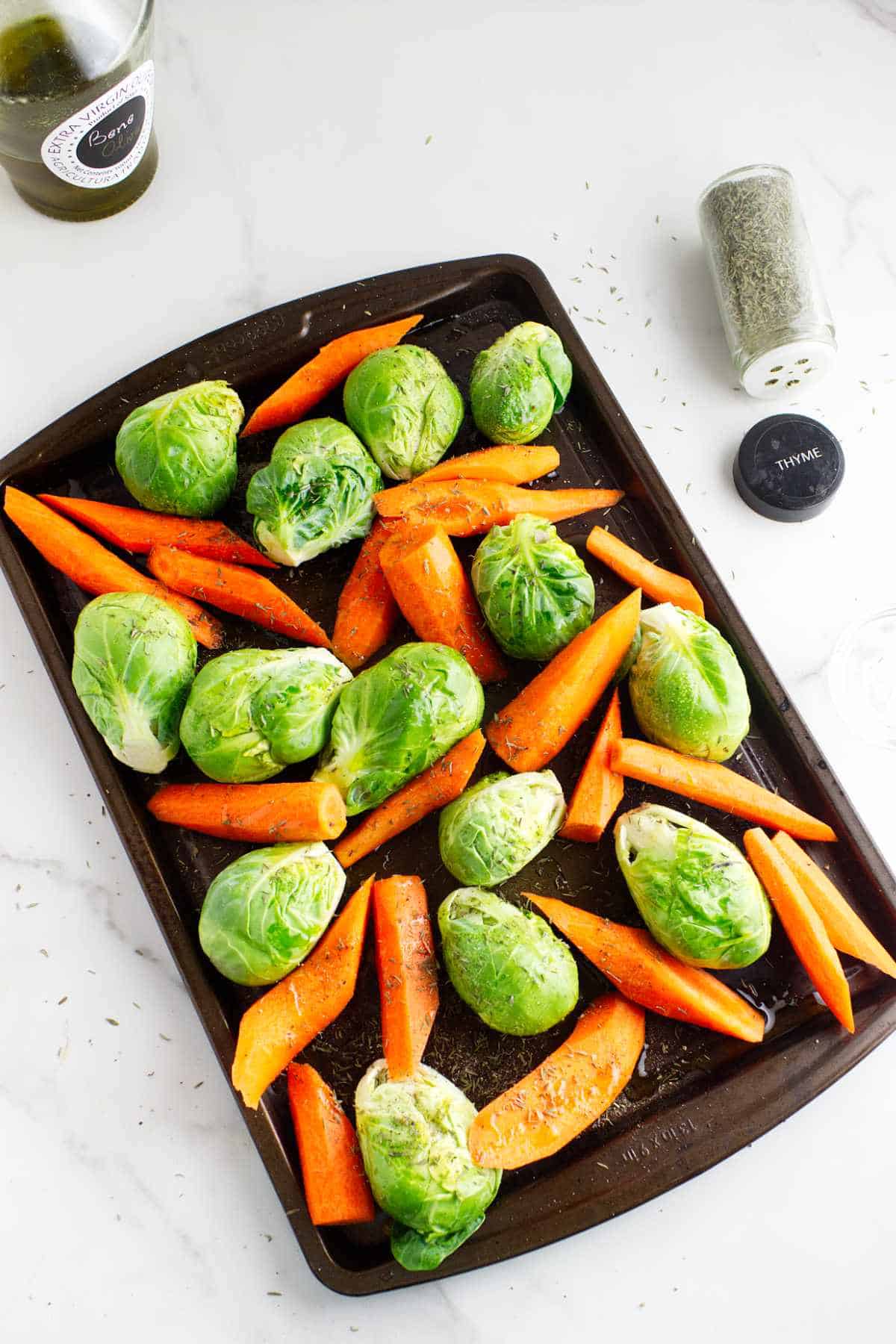 Sheet pan of seasoned carrots and brussels sprouts.