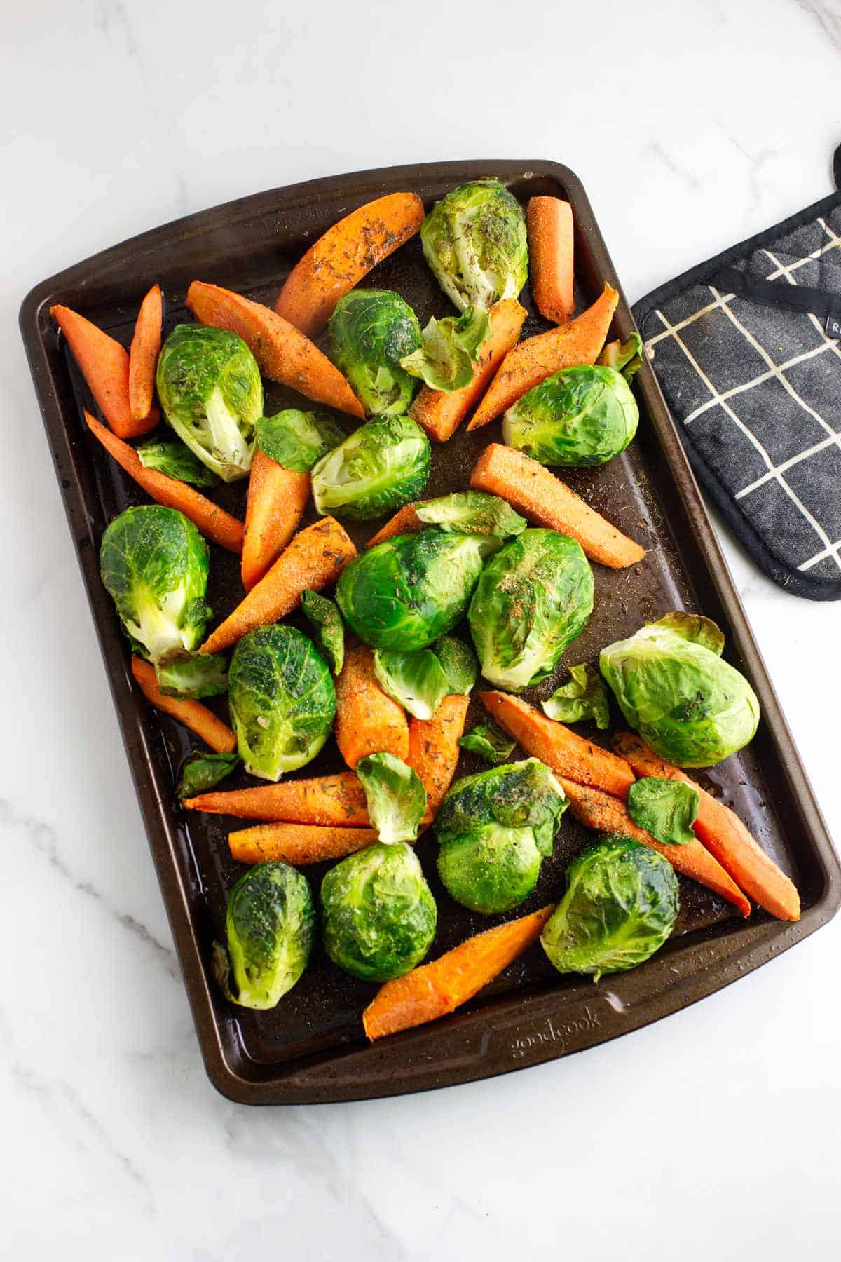 Roasted pan of seasoned carrots and brussels sprouts.