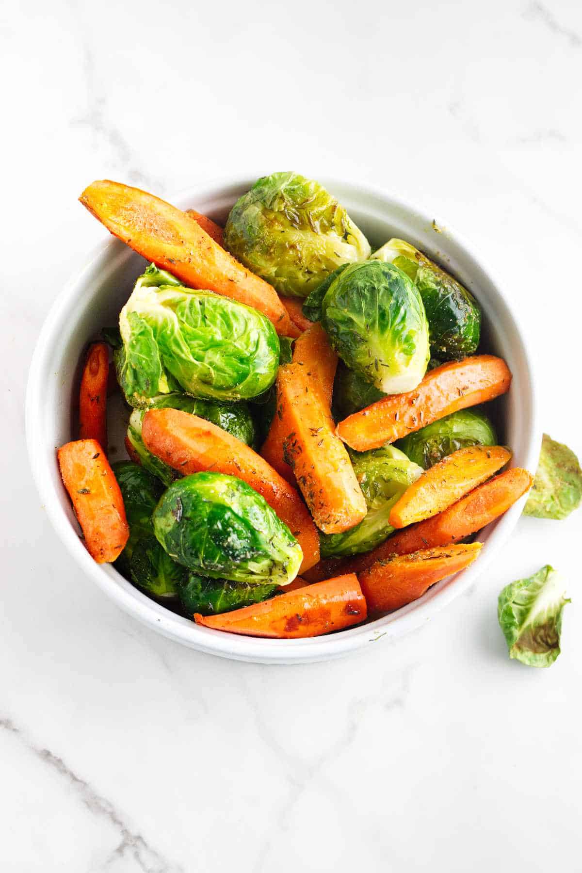 Serving bowl of roasted carrots and brussels sprouts.
