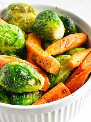 Serving bowl of roasted carrots and brussels sprouts.